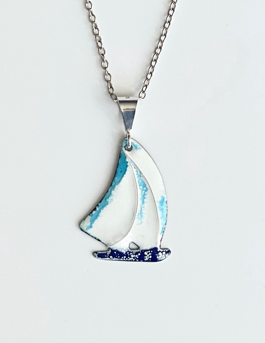 Sailboat-shaped pendant on a chain against a light gray background