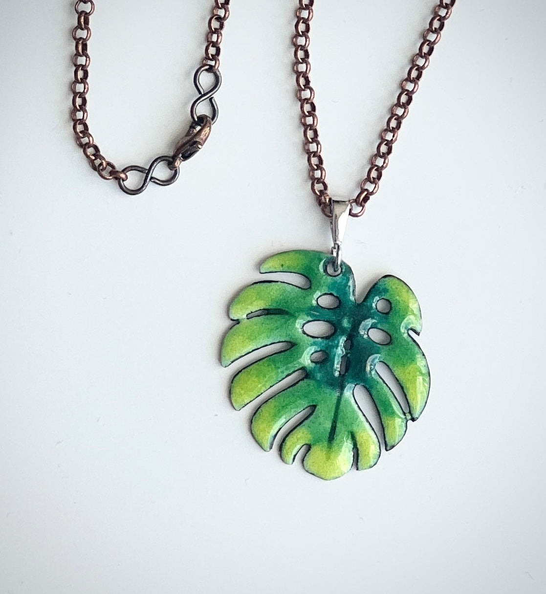 Necklace with a green leaf pendant on a white background. Copper hain