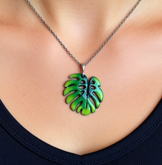 Green leaf-shaped pendant on a chain worn around the neck. Silver chain