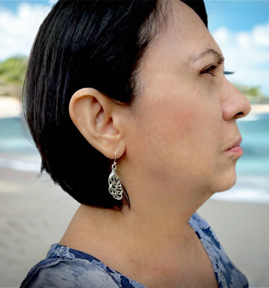 model wearing silver leaf earrings with ocean behind