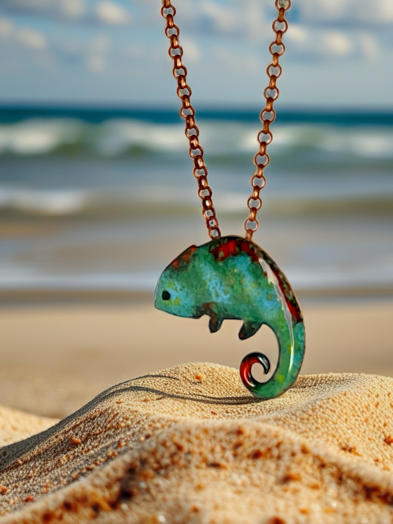 Chameleon-shaped necklace on a sandy beach with ocean in the background