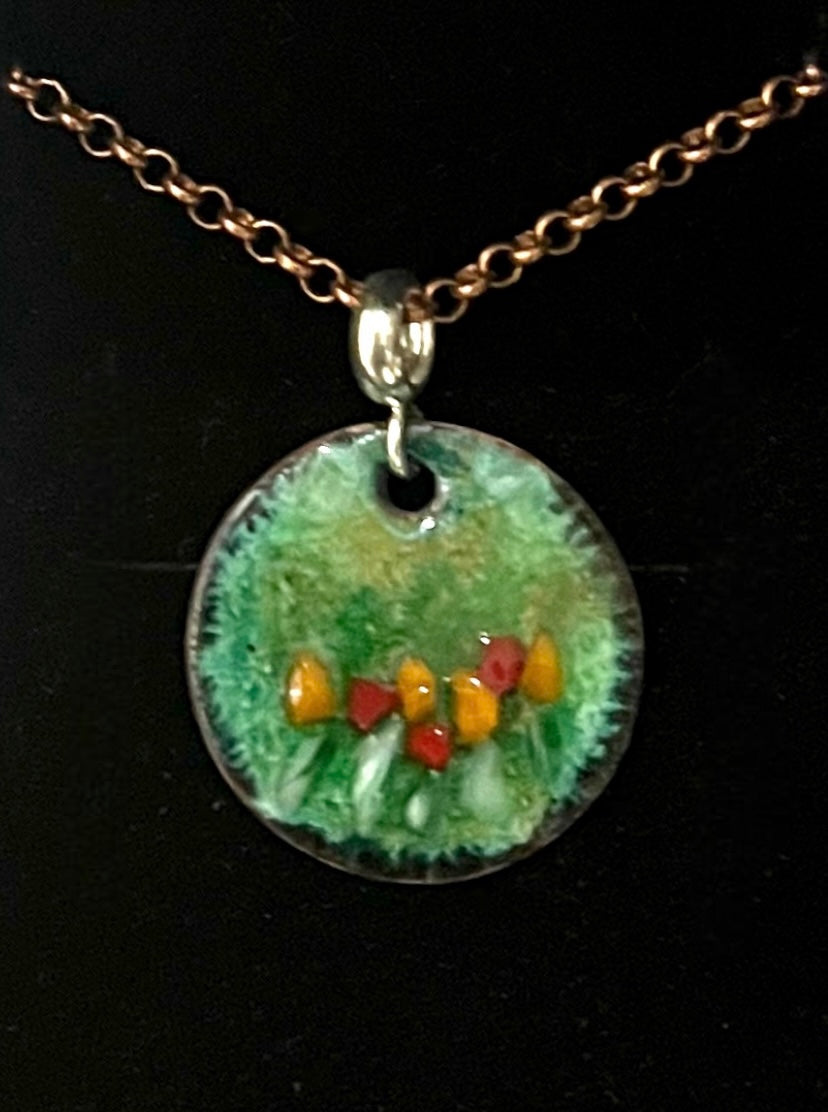 Round pendant with nature-themed design on a chain against a black background