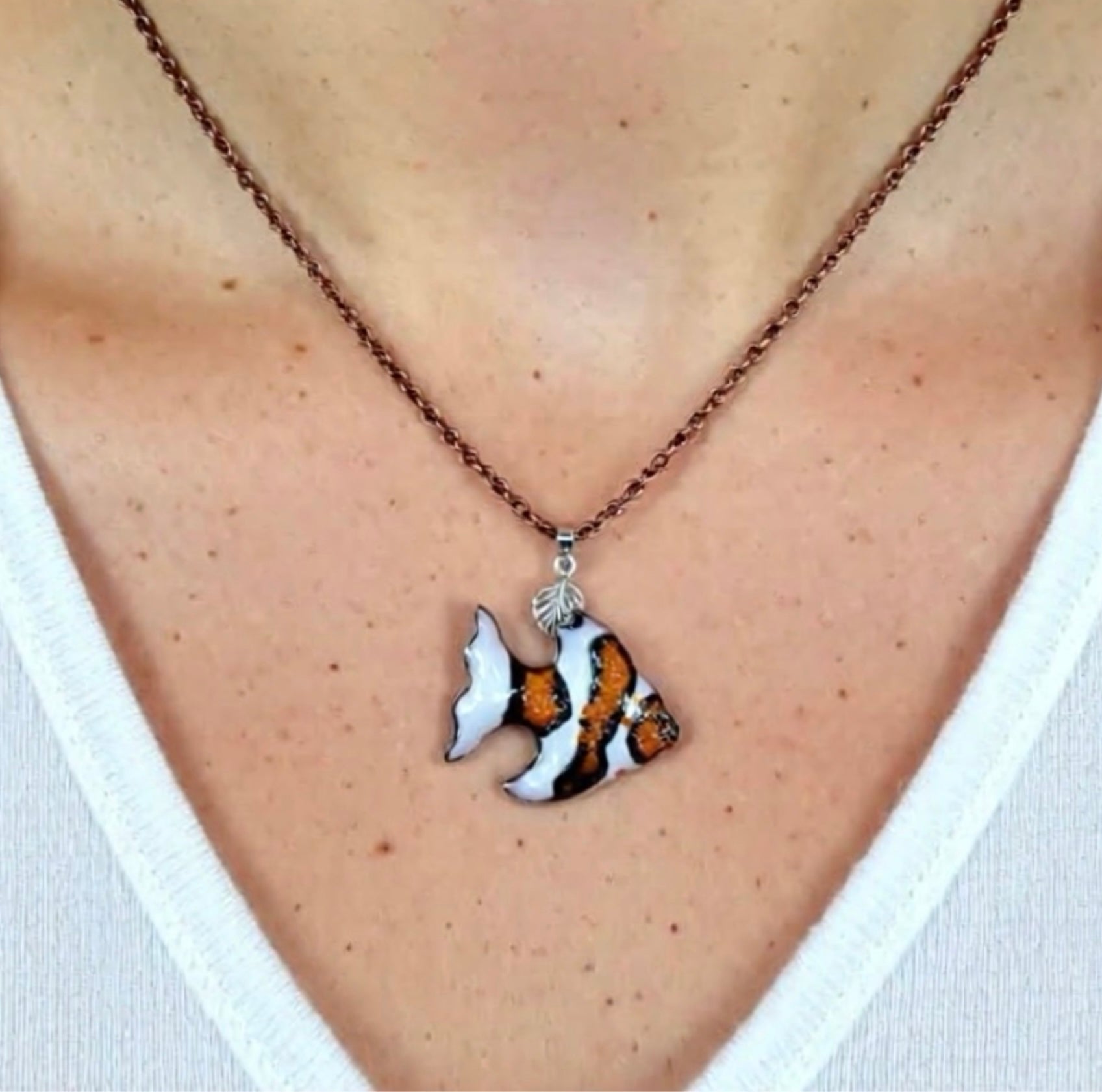 Necklace with a fish pendant worn by a person, copper chain