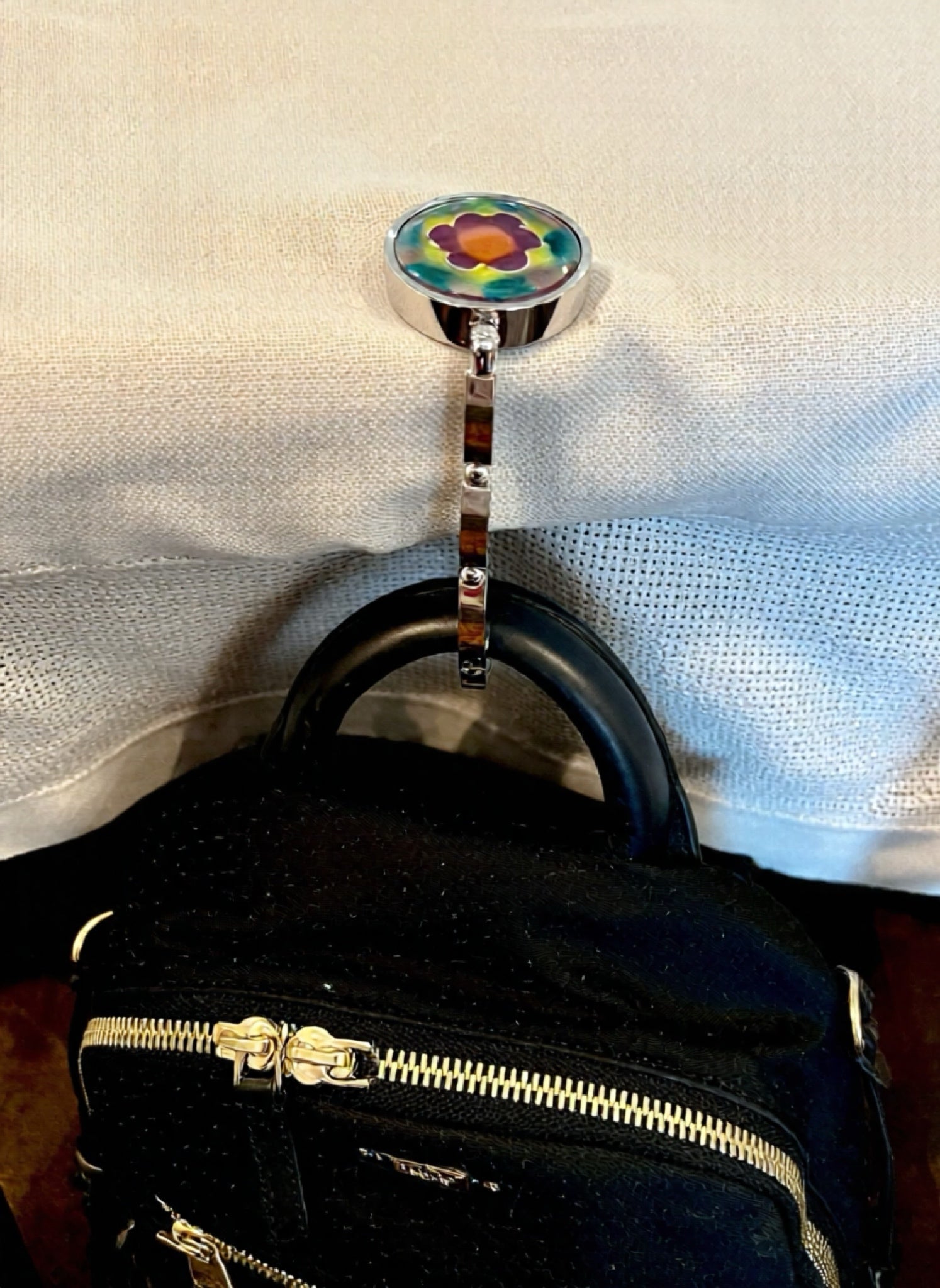 Black handbag with a colorful floral hook on a white background