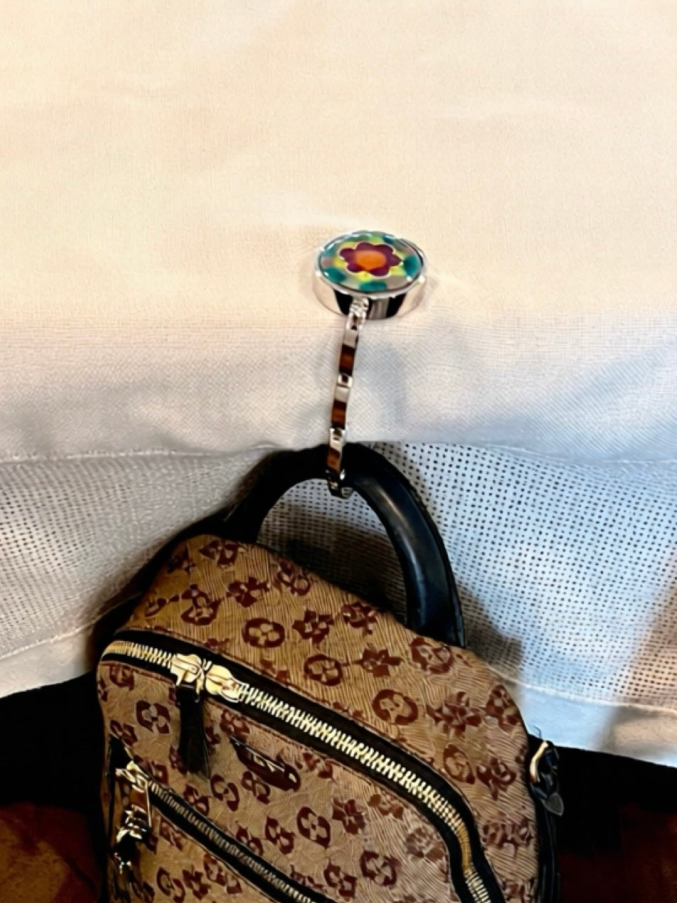 Handbag with a floral-patterned hook on a white background