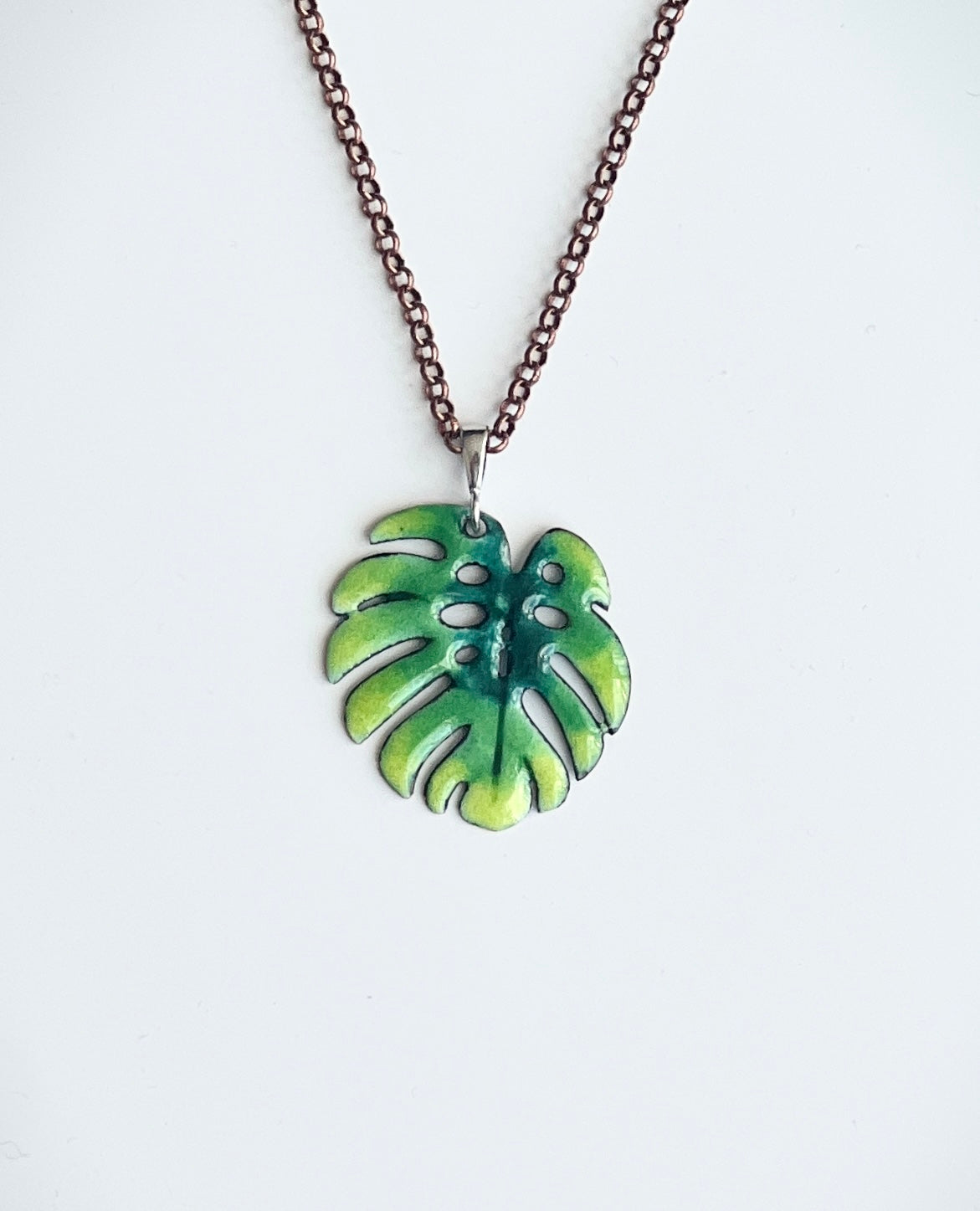 Necklace with a green leaf-shaped pendant on a white background, monstera leaf