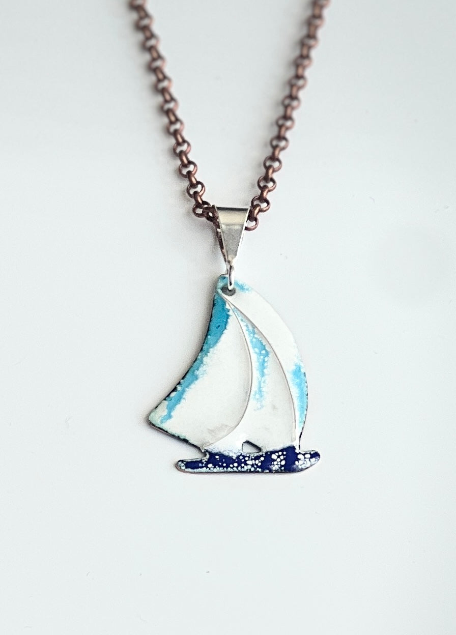 Sailboat pendant on a chain against a white background
