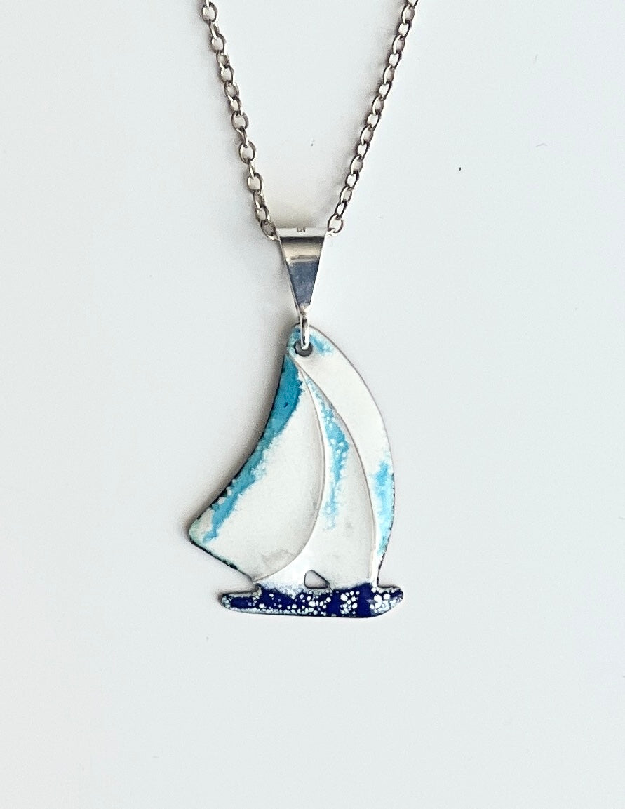 Sailboat-shaped pendant on a chain against a white background