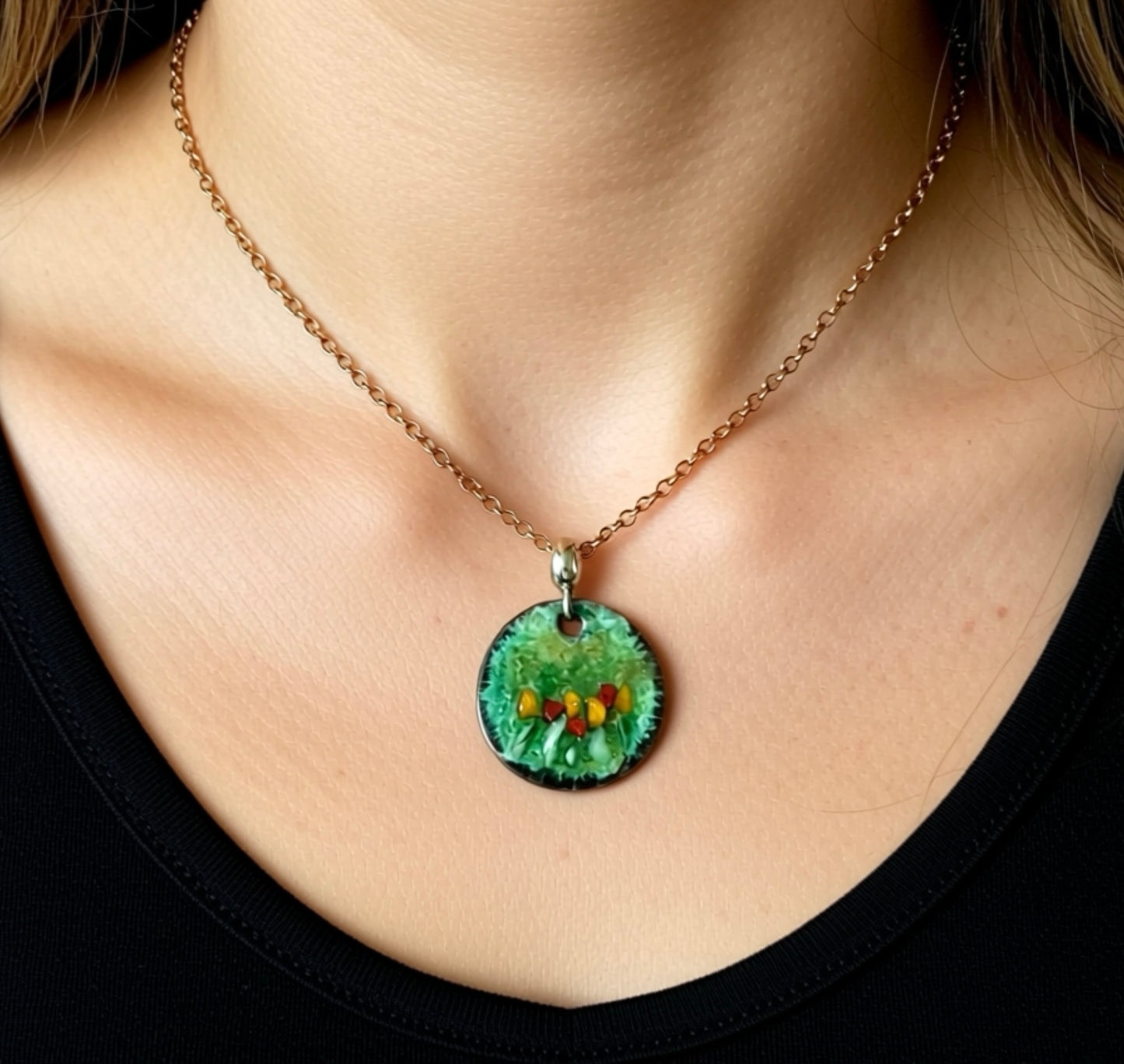 Necklace with a green pendant featuring small colorful stones worn by a person.