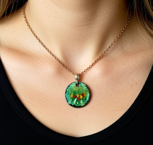 Necklace with a green pendant featuring small colorful stones worn by a person.