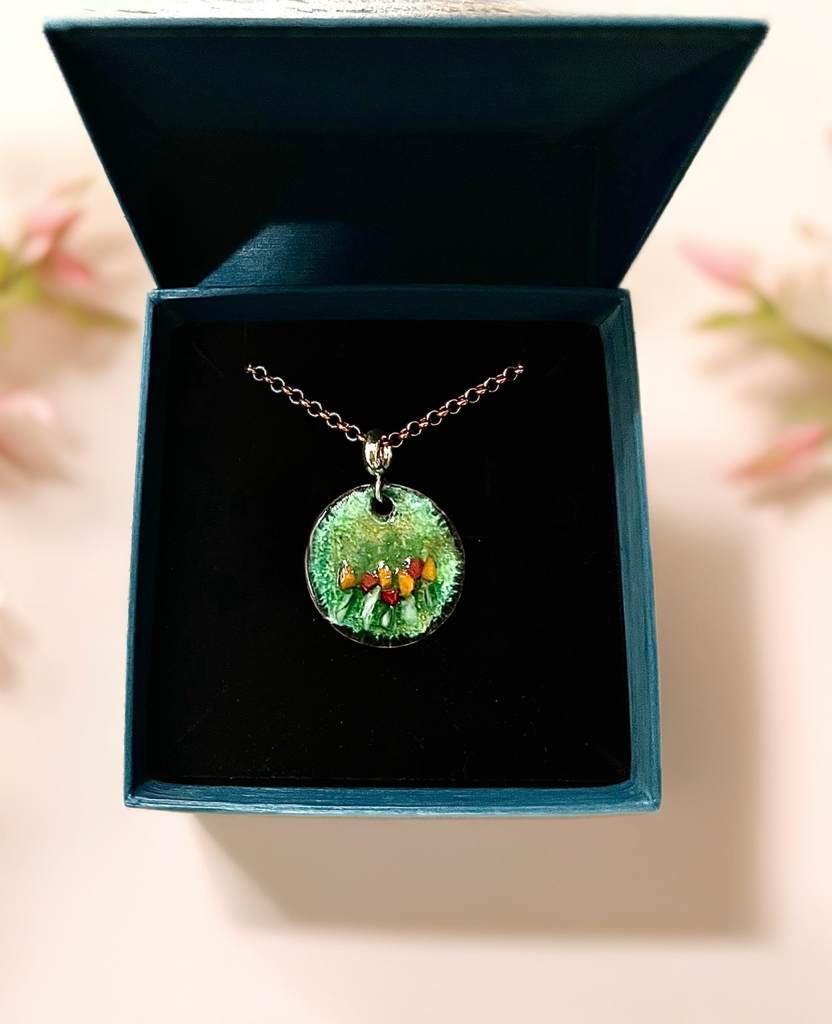 Necklace with a green pendant in an open teal box on a light background