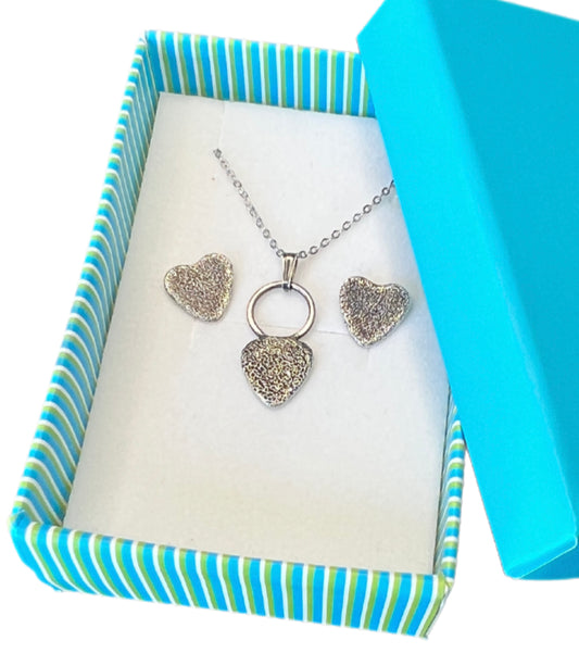 Heart-shaped jewelry set with necklace and earrings in a striped box.