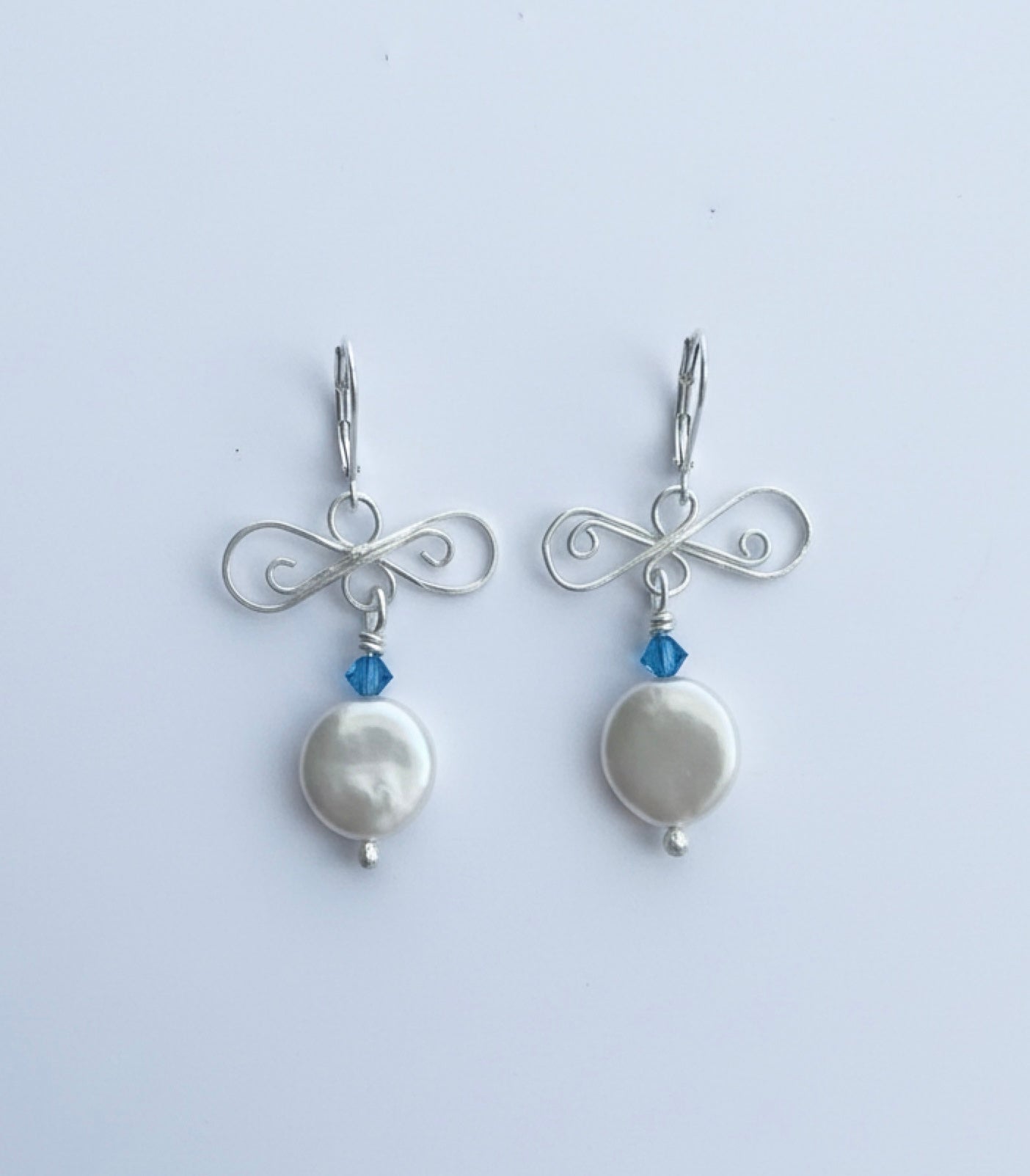 silver and pearl earrings on white background