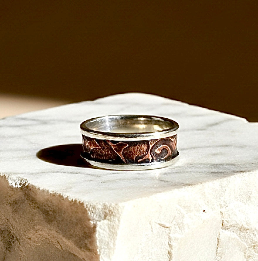 Silver ring with engraved design on a marble surface
