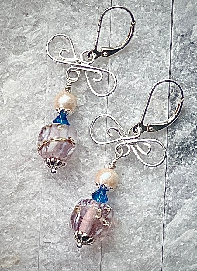 Pair of earrings with glass beads and metal hooks on a textured surface