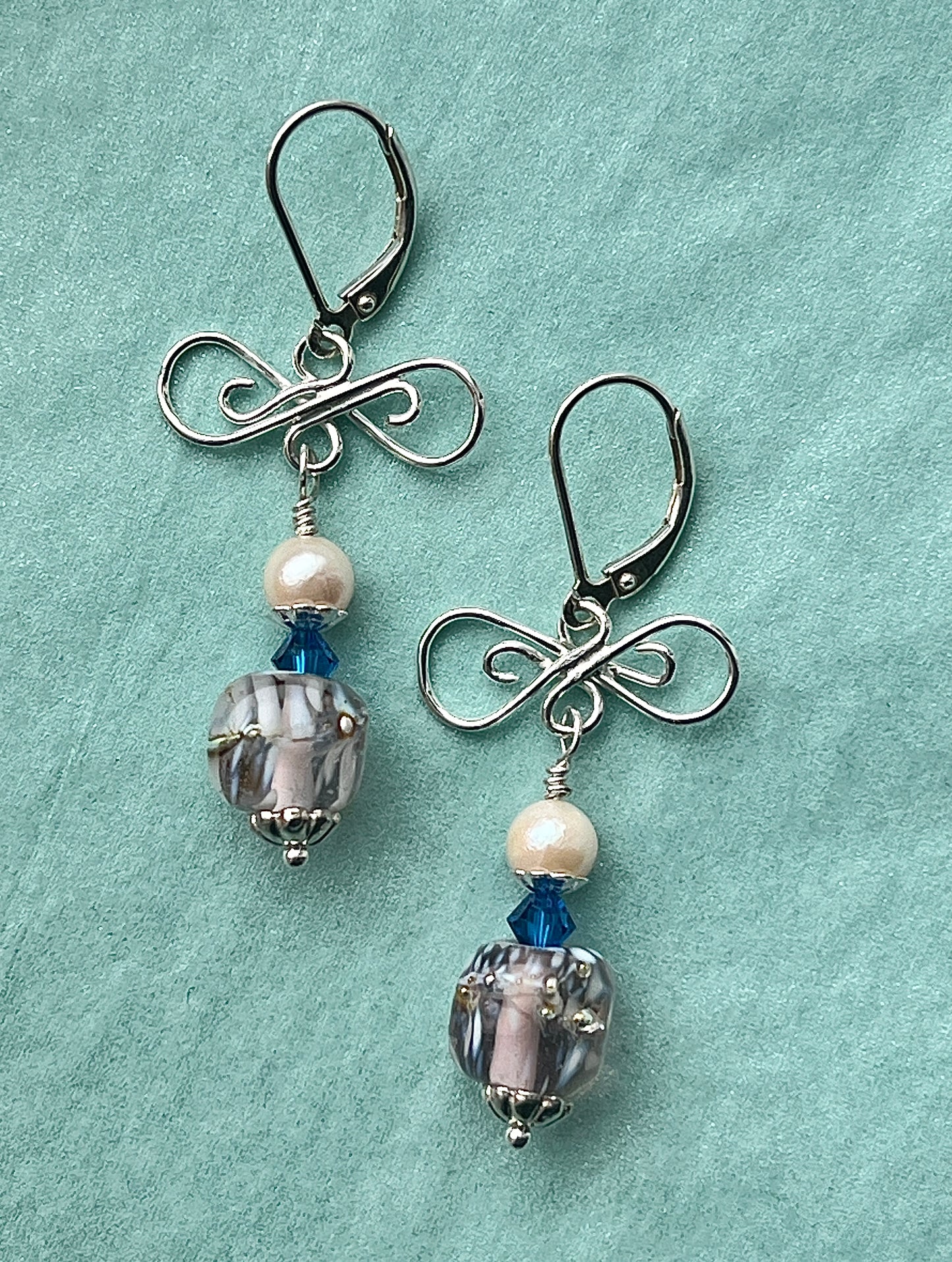 Pair of earrings with blue and clear beads on a teal background
