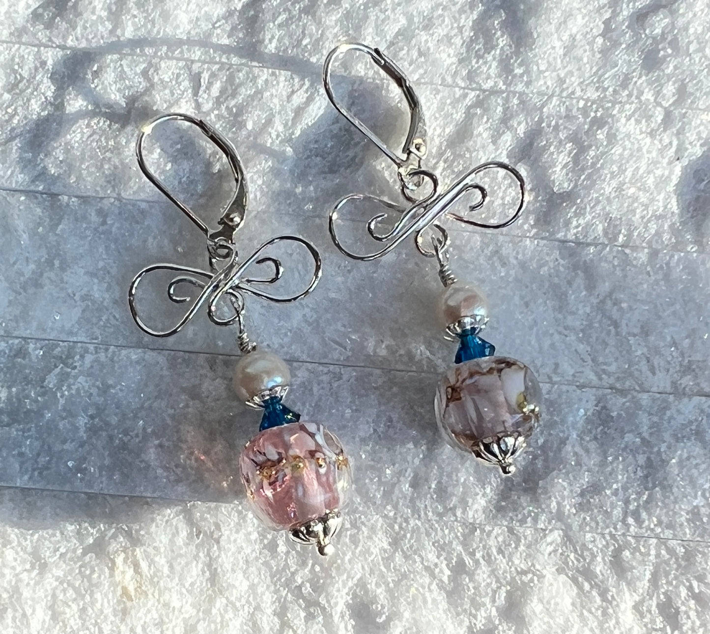 Pair of silver earrings with glass beads on a textured surface