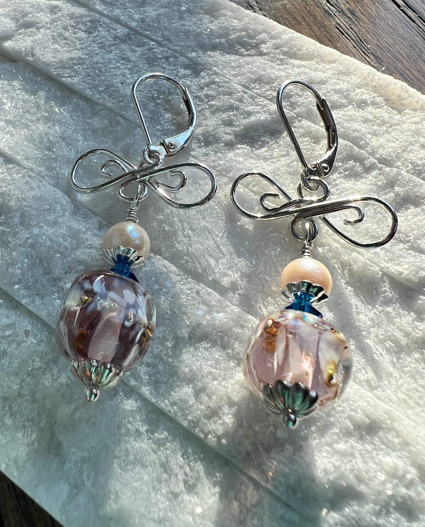 Pair of silver earrings with glass beads on a marble surface