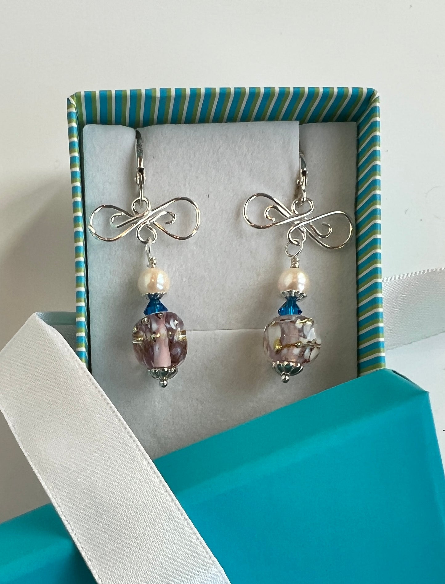 Silver earrings with gemstones in a striped box