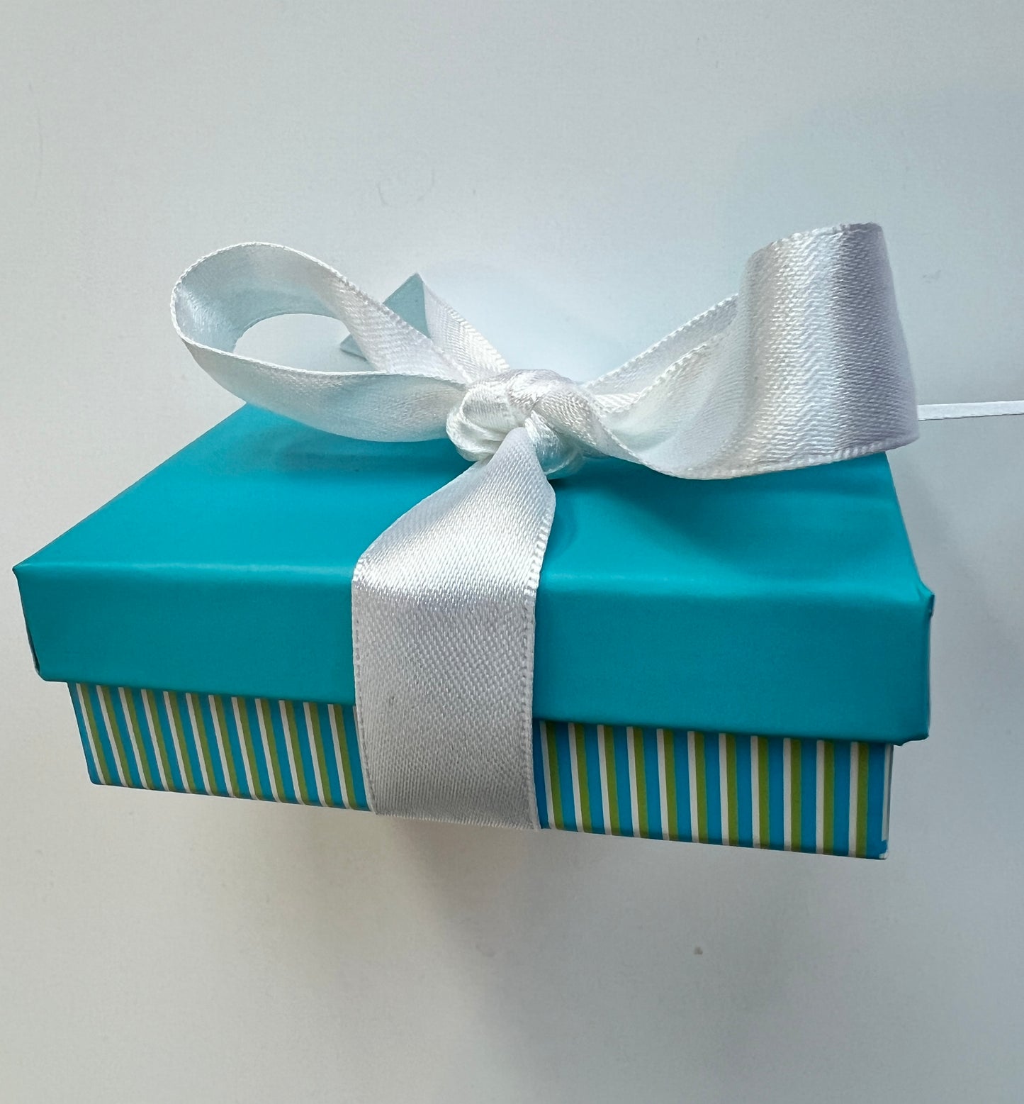 Blue gift box with a white ribbon on a light gray background