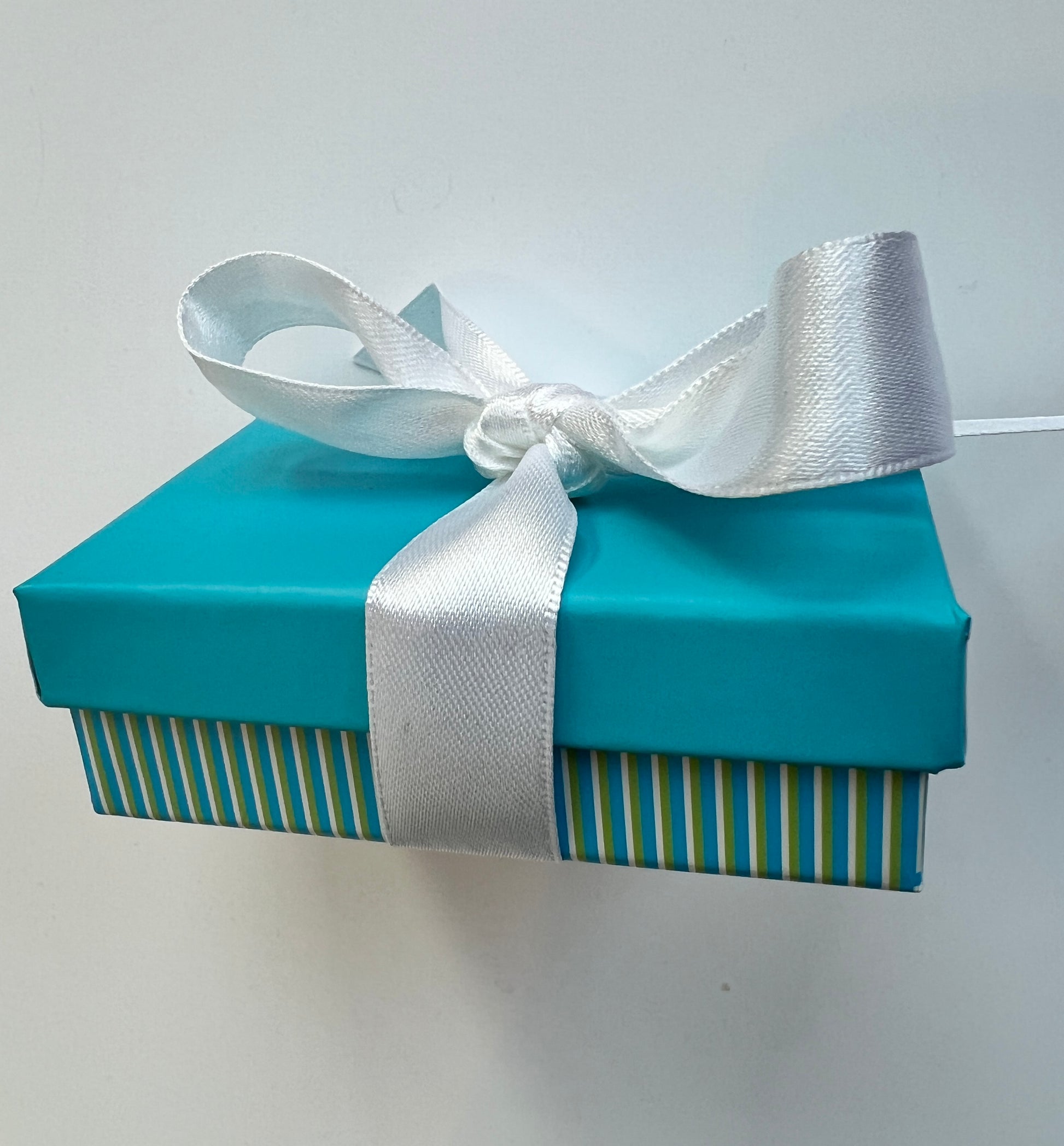 Blue gift box with a white ribbon on a light gray background