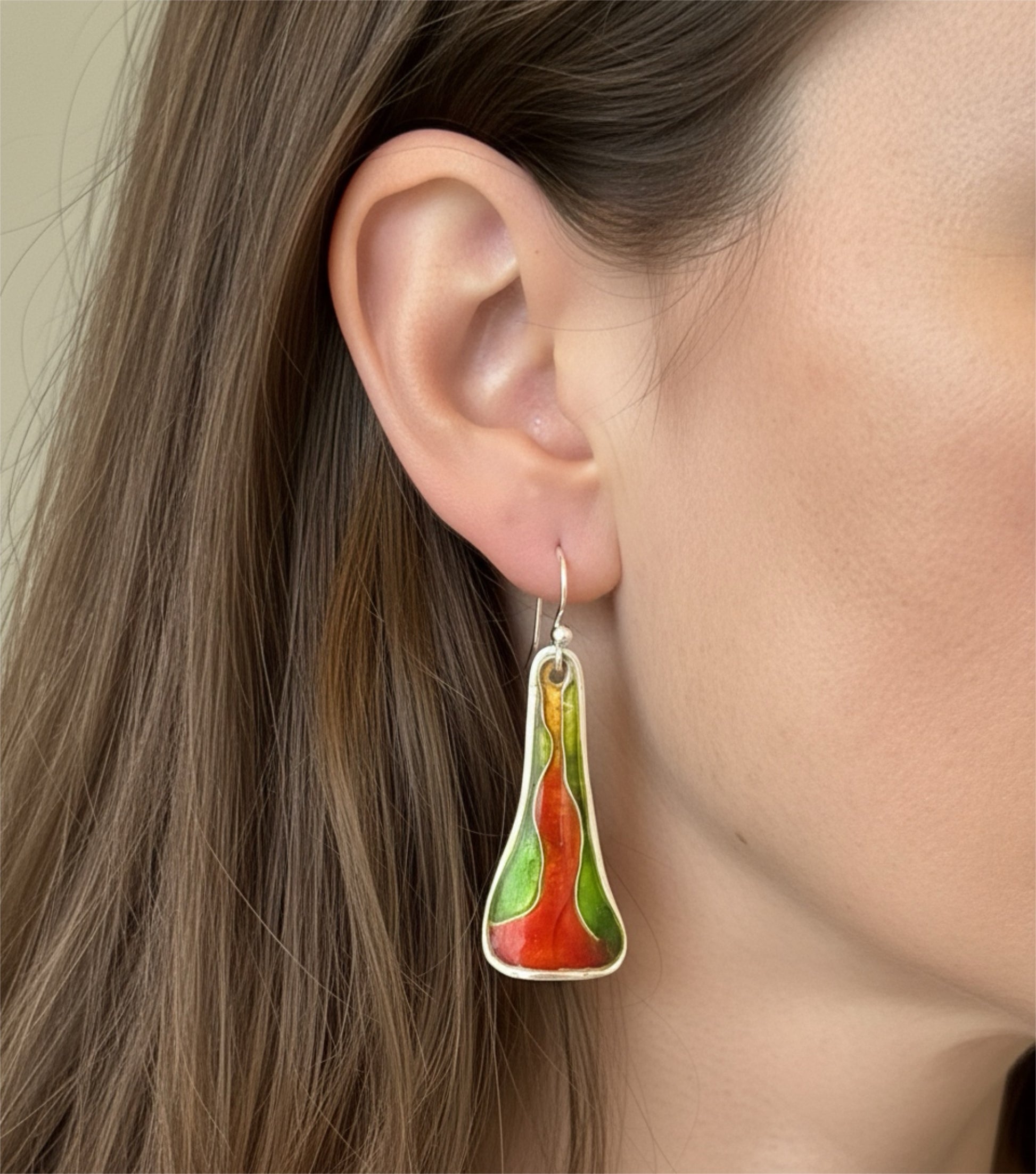 Close-up of a person wearing a colorful earring with a neutral background