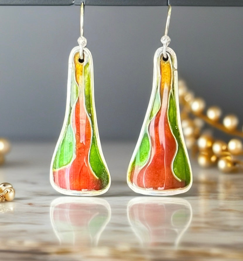 Colorful teardrop-shaped earrings on a reflective surface with a neutral background