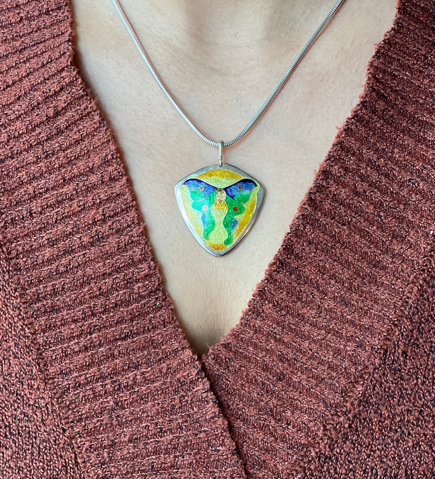 Necklace with a colorful pendant on a brown textured fabric background