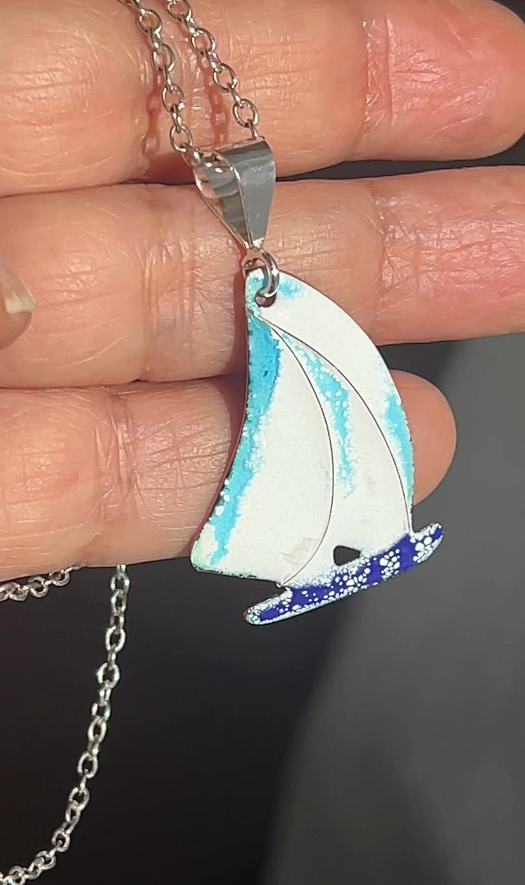 Hand holding sailing boat pendant
