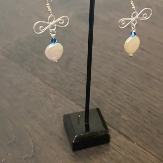 video showing pair of aearrings silver and pearl from different angels hanging from a frame