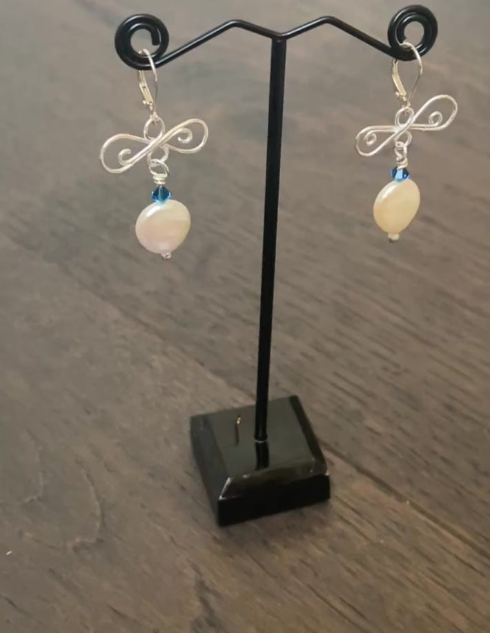 video showing pair of aearrings silver and pearl from different angels hanging from a frame