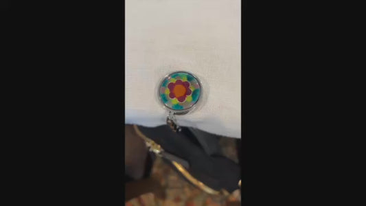 Video showing a black backpack hanging at a table from an enamel decorated hadbag hanger
